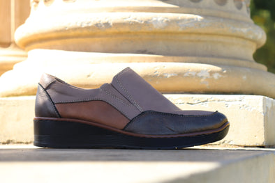 A brown and gray women's slip-on shoe with a low wedge heel.